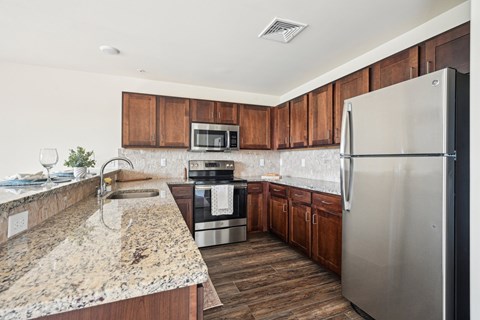 A kitchen with a granite countertop and stainless steel appliances.