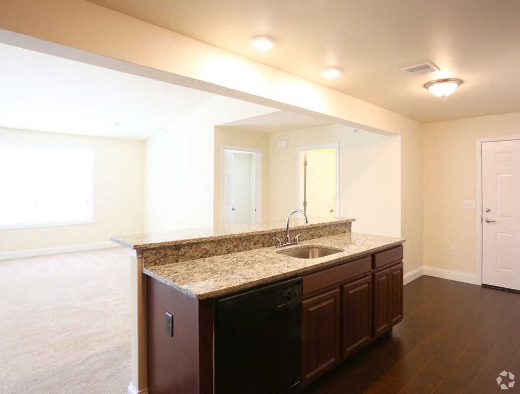 an empty kitchen with a granite counter top and a sink