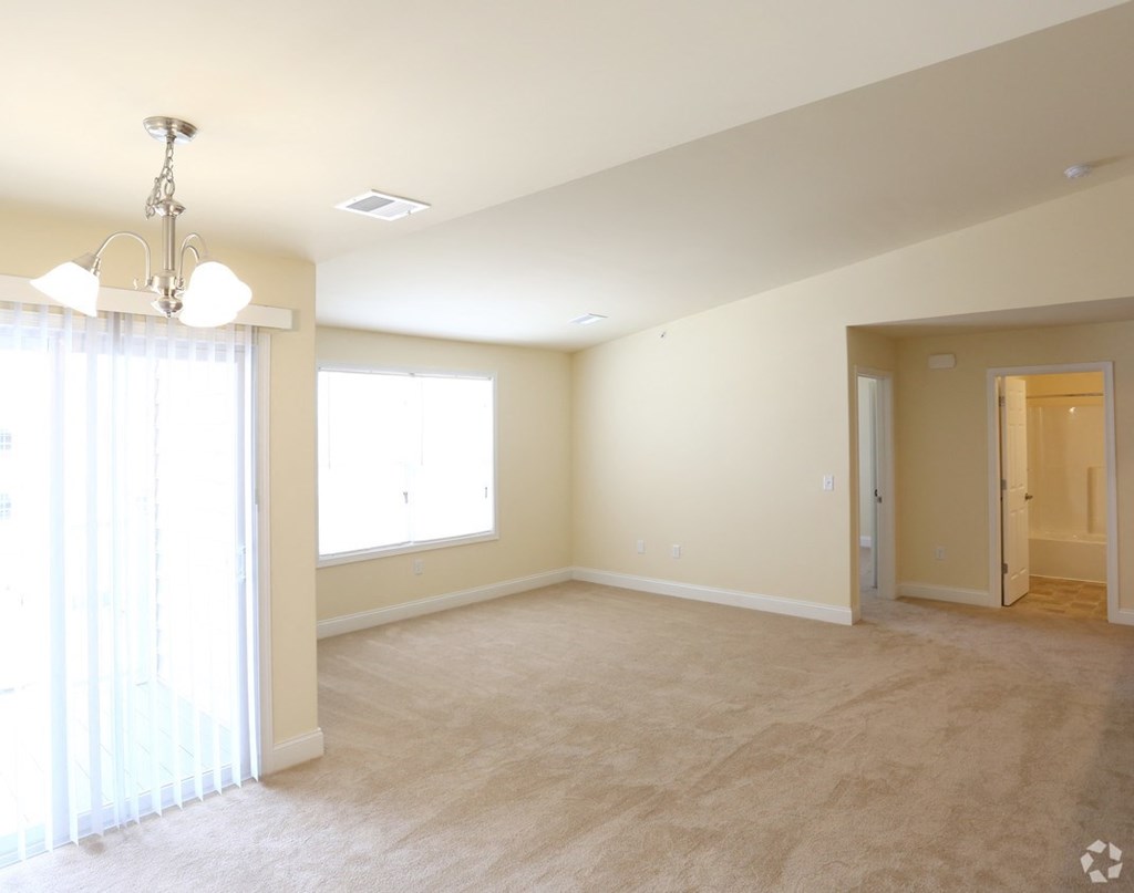 an empty living room with a window and a chandelier