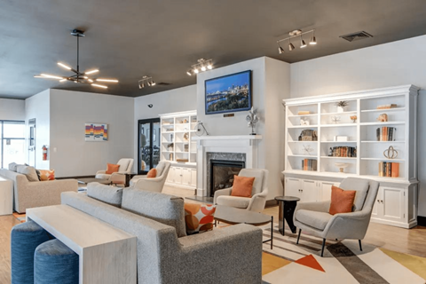 A living room with a grey sofa, a fireplace, and a painting on the wall.