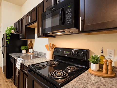 A black microwave is mounted above a black stove in a kitchen.