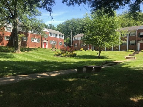 a green yard with benches in front of a brick building