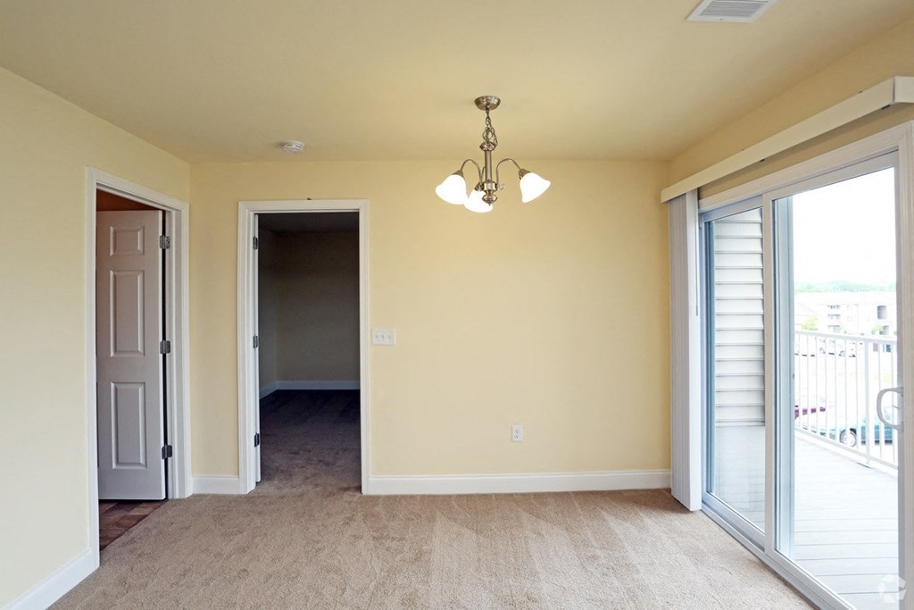 an empty living room with sliding glass doors and a chandelier