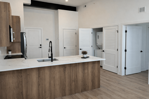 A modern kitchen with a wooden counter and white cabinets.