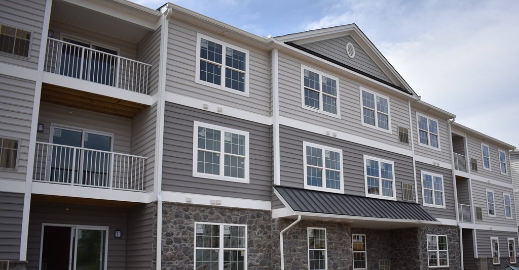 an apartment building with gray siding and a stone facade