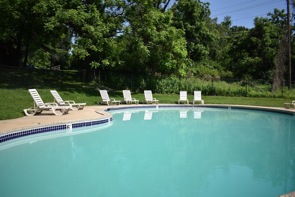 a swimming pool with chaise lounge chairs in the grass