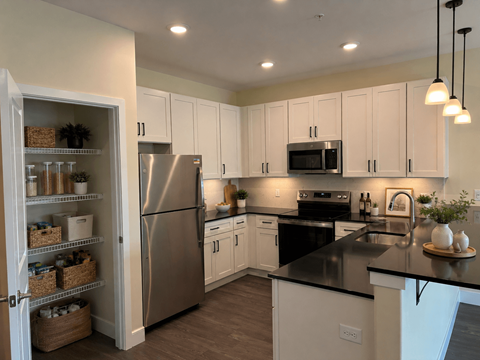 A kitchen with white cabinets and a black countertop.