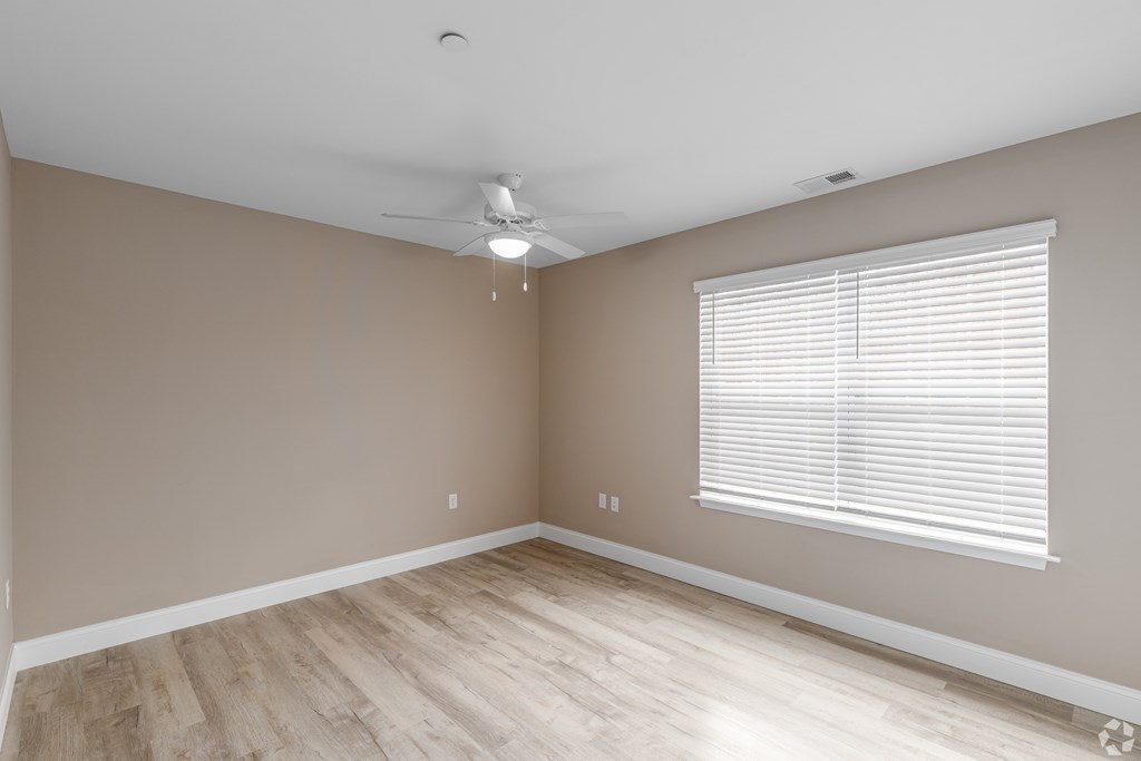 A room with a ceiling fan and a window with blinds.