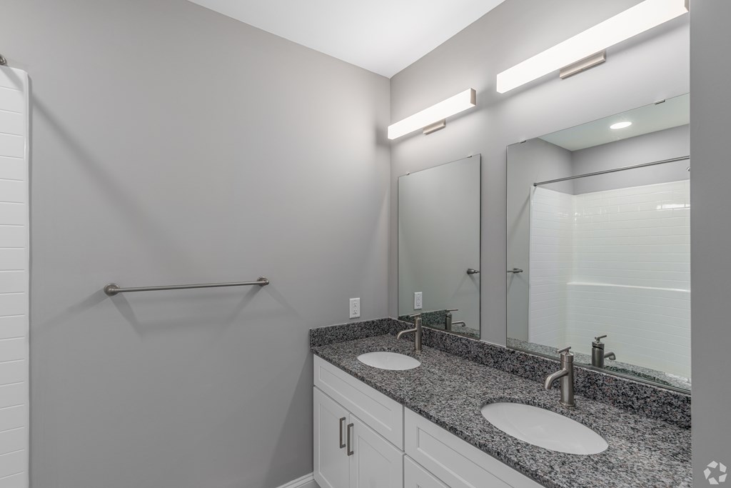 A bathroom with a sink, mirror, and lighting fixtures.