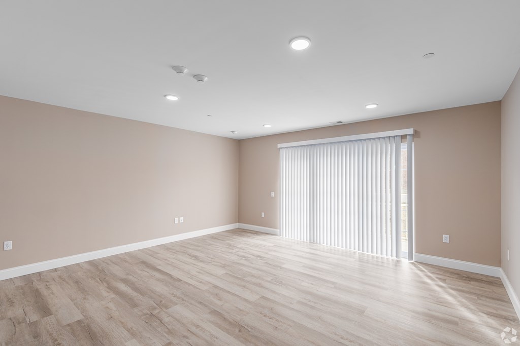 A room with wooden flooring and a window with blinds.