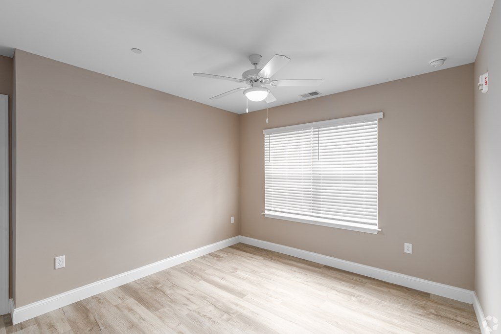 A room with a ceiling fan and a window with blinds.