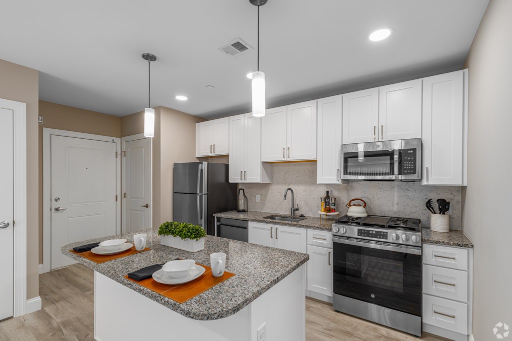 A modern kitchen with a granite countertop and stainless steel appliances.