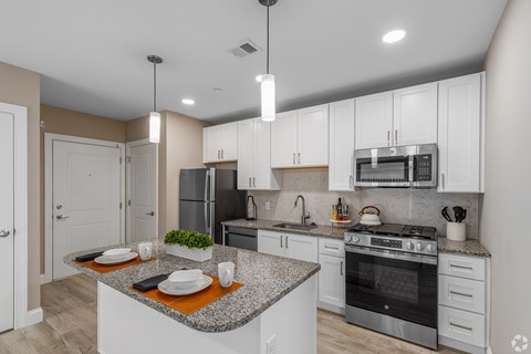 A modern kitchen with a granite countertop and stainless steel appliances.