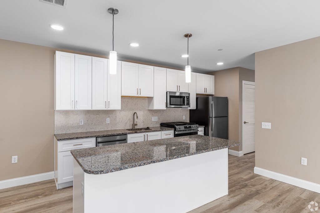 A kitchen with a granite countertop and white cabinets.