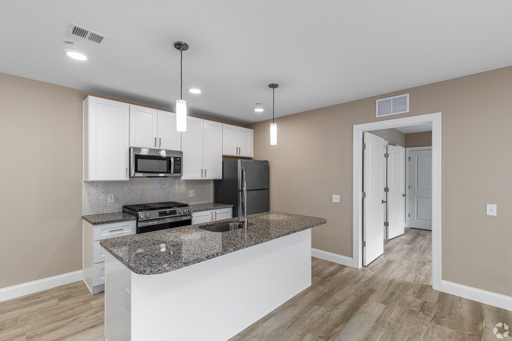 A kitchen with a granite countertop and stainless steel appliances.
