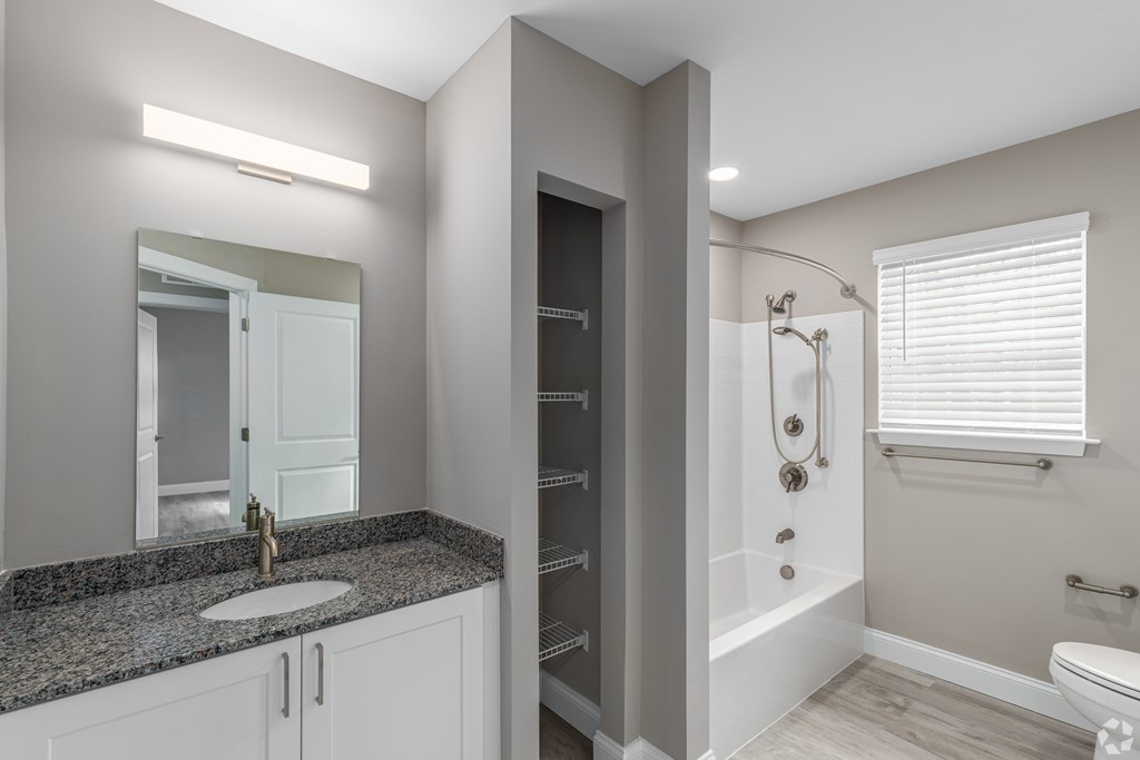 A bathroom with a sink, mirror, and shower.