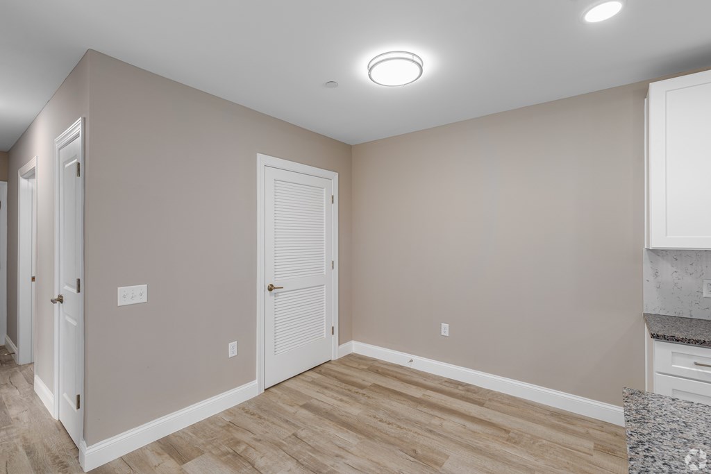 A room with a white door and a wooden floor.
