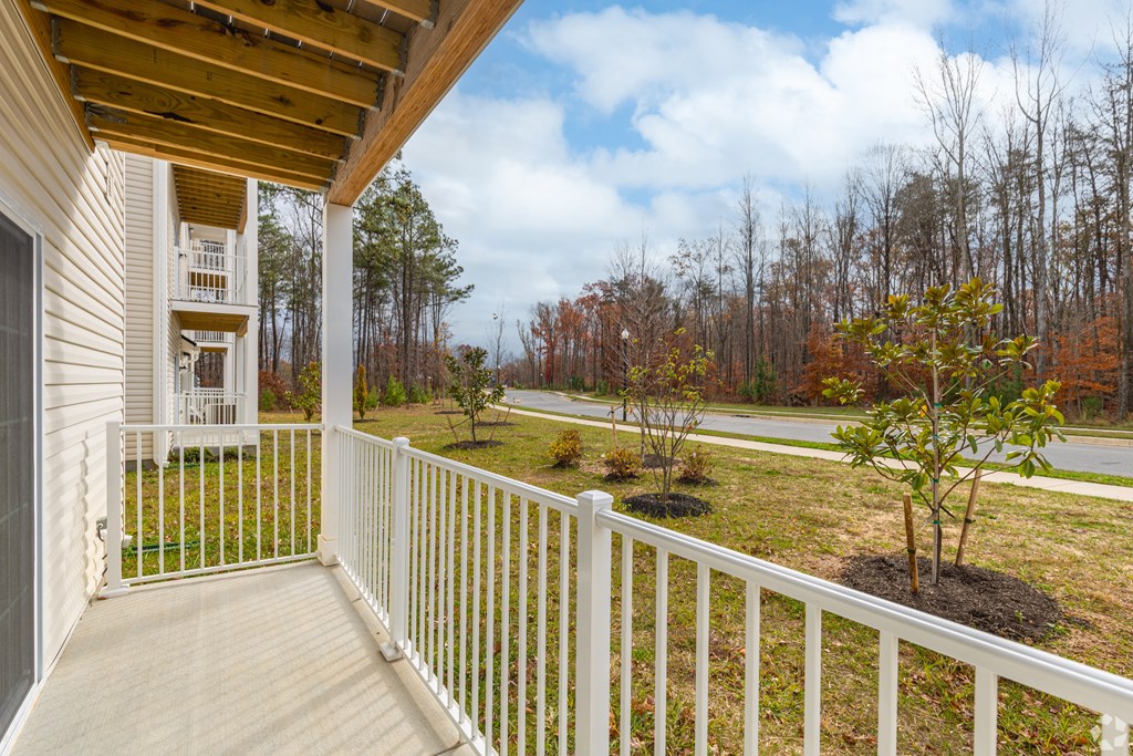 A small tree is planted in a flower bed on a porch.