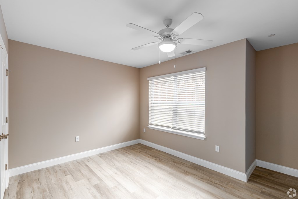 A room with a ceiling fan and a window with blinds.
