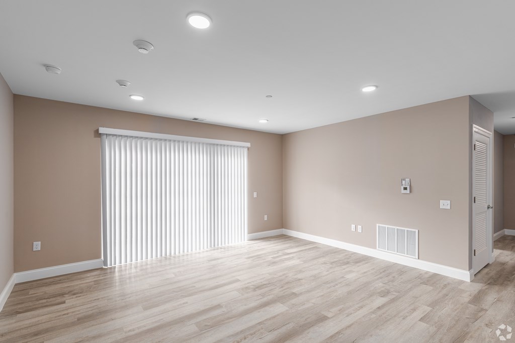 A room with wooden flooring and a window with blinds.