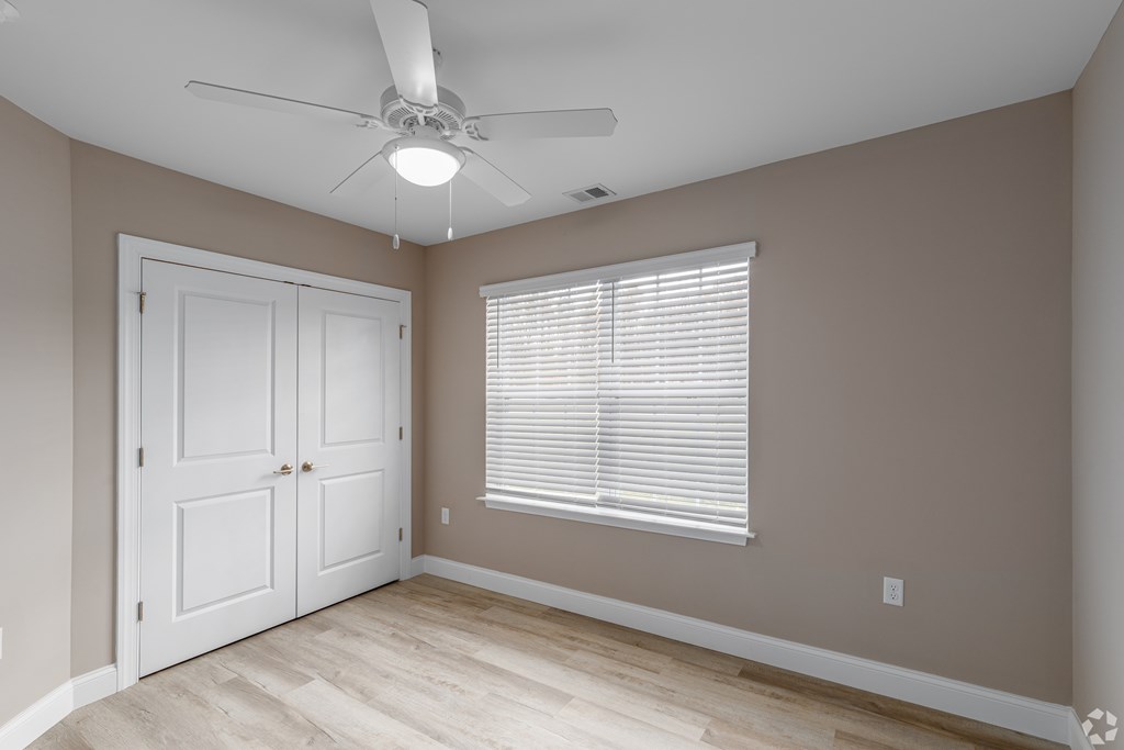 A room with a ceiling fan and a window with blinds.