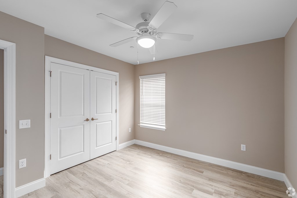 A room with a ceiling fan and a door.
