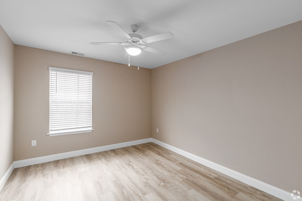 A room with a ceiling fan and a window with blinds.