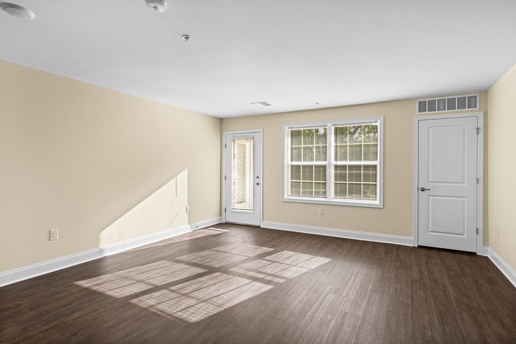 an empty living room with wood flooring and a door