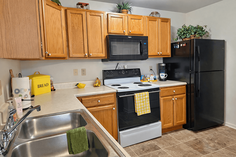 A kitchen with a black refrigerator and a black stove top oven.