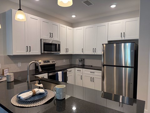 A modern kitchen with a stainless steel refrigerator and white cabinets.