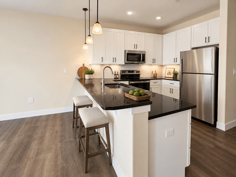 A kitchen with white cabinets and a black countertop.