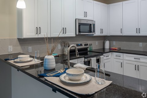 A kitchen with white cabinets and a black countertop.