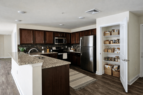 A kitchen with a granite countertop and a refrigerator with baskets of food on the door.