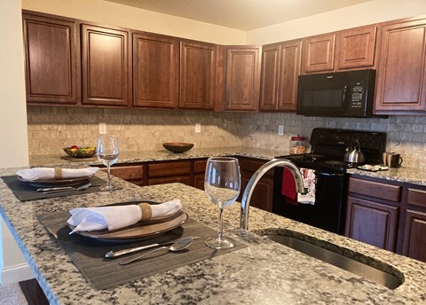 a kitchen with a sink and a counter with wine glasses