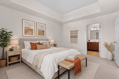 A bedroom with a large bed and a plant on the side table.