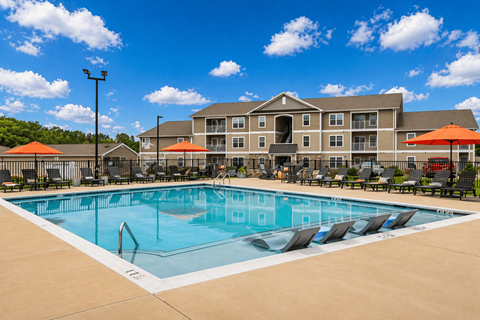 A large swimming pool in front of a multi-story apartment building.