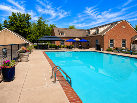 A swimming pool surrounded by a brick building and a patio area.