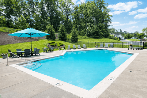 A large blue pool with a white border and a white umbrella.