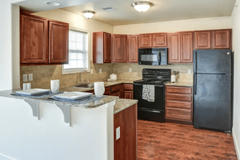 A kitchen with brown cabinets and black appliances.