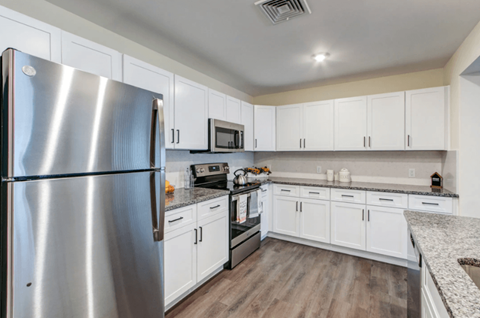 A modern kitchen with a stainless steel refrigerator and white cabinets.