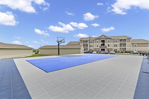 A basketball court with a blue surface and a basketball hoop.
