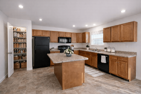A kitchen with a black refrigerator and wooden cabinets.