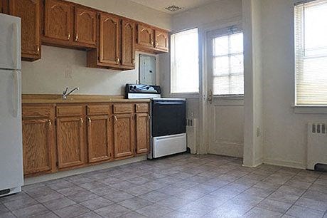 an empty kitchen with wooden cabinets and a refrigerator