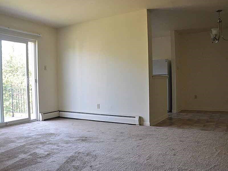 an empty living room with white walls and a sliding glass door