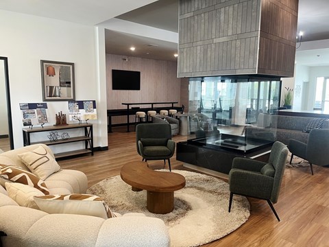 A modern living room with a glass coffee table and a grey sofa.