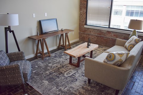 A living room with a couch, chair, and a table with a television on it.