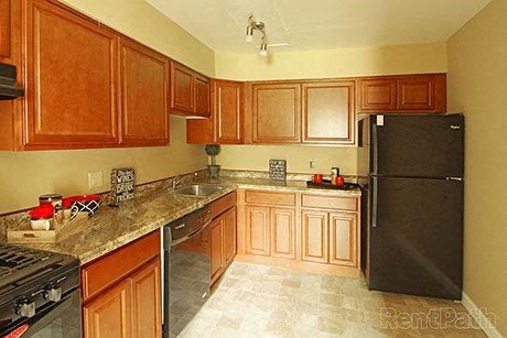 a kitchen with wooden cabinets and a black refrigerator