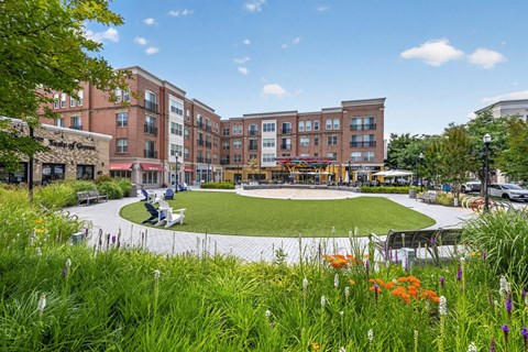 A grassy area with flowers in the foreground and a building in the background.