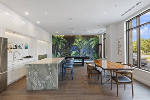 A kitchen with a marble island and a dining table with chairs.