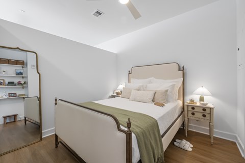 A bedroom with a bed, nightstand, and a mirror.